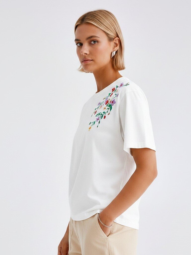 Woman wearing a LoomBasics white 100% cotton tee with colorful floral embroidery