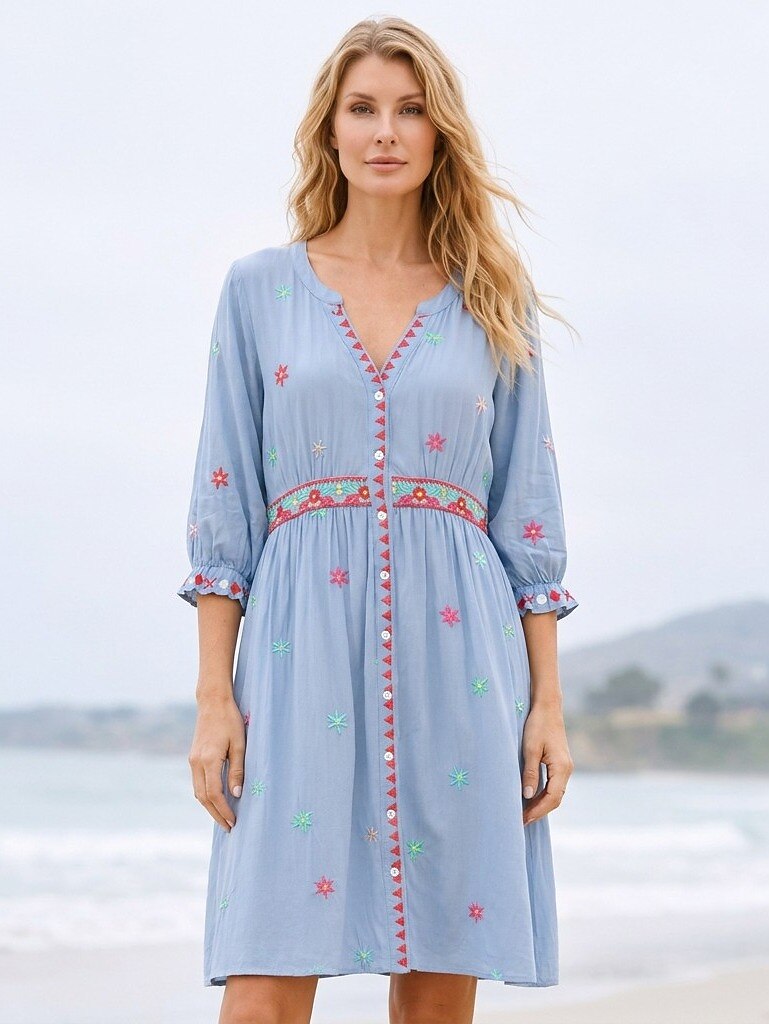 Woman wearing a LoomBasics light blue embroidered 100% cotton mini dress on a beach.