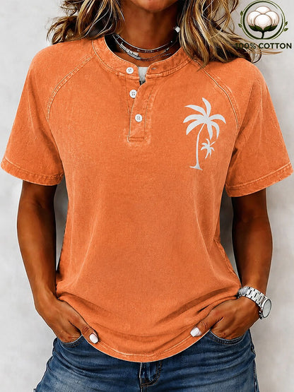 Woman wearing a LoomBasics orange washed 100% cotton Henley tee with a white palm tree graphic.
