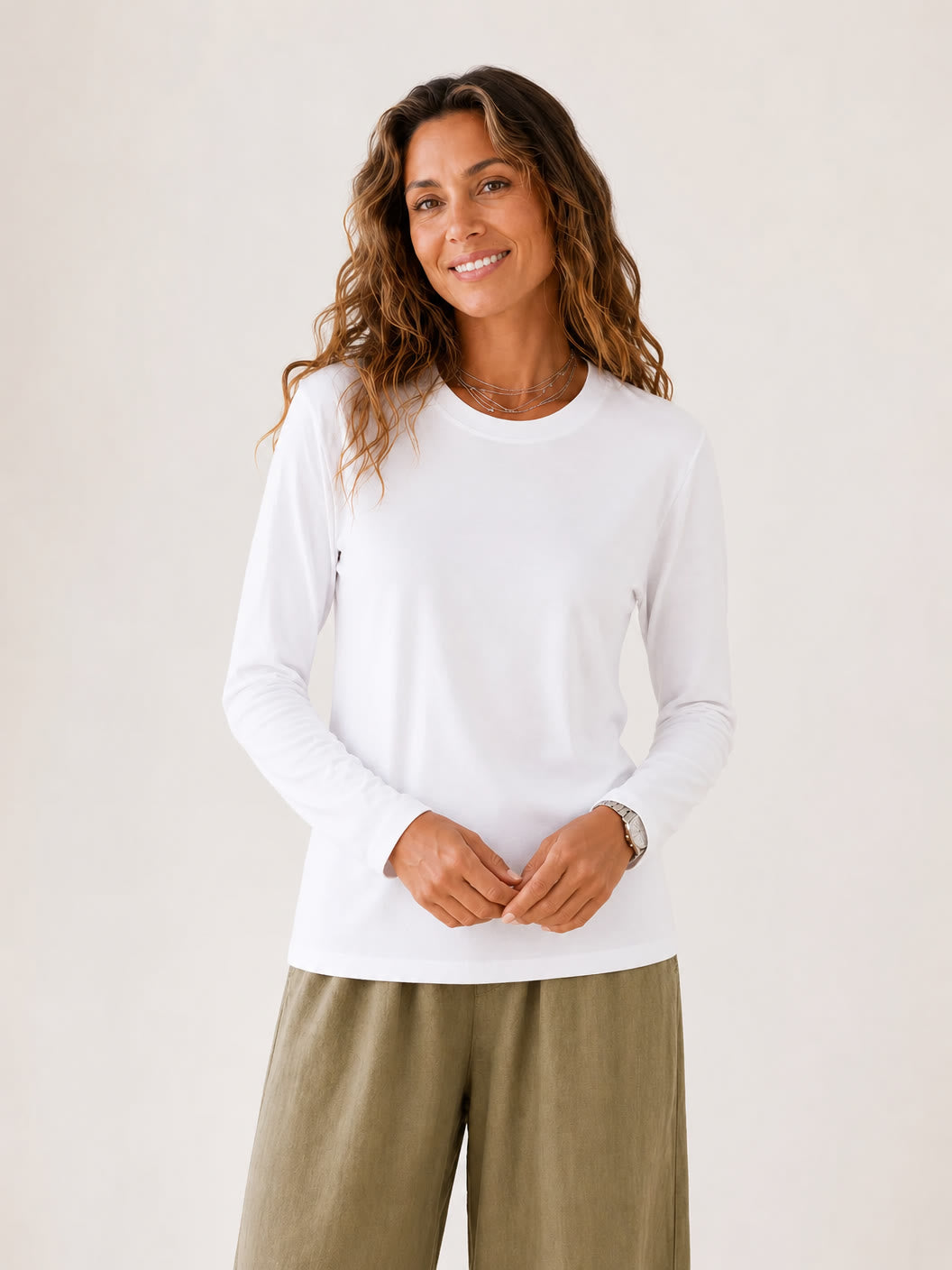 Woman wearing a white LoomBasics 100% cotton crew neck long sleeve tee and olive wide-leg pants.