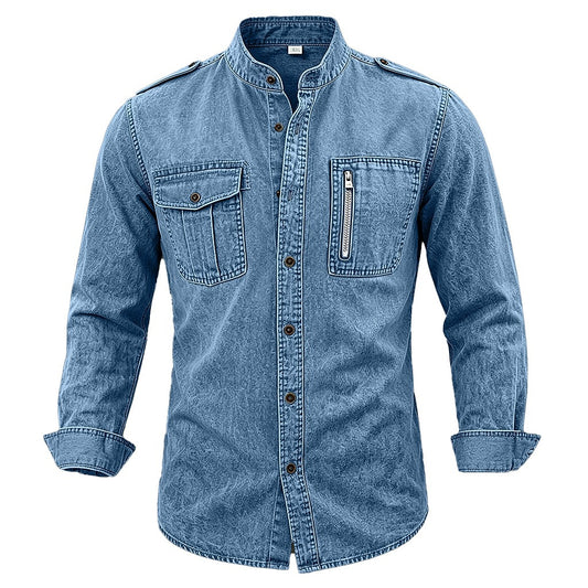 A men's long-sleeve denim shirt jacket in a medium blue wash, featuring a stand collar, button-down front, two flap chest pockets, and a zippered chest pocket, shown on a plain white background.